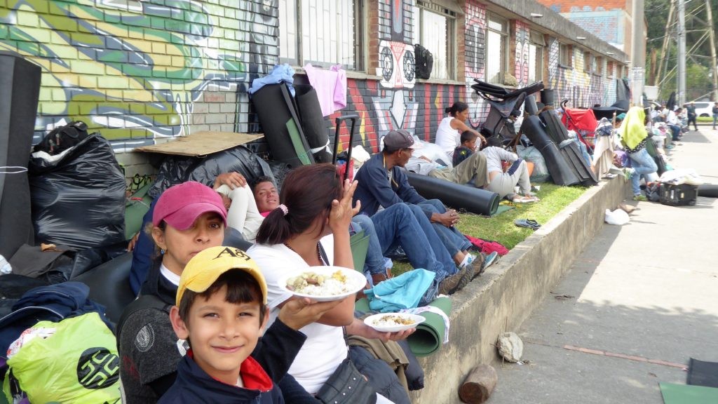 ﻿Recently-arrived migrants wait in the sun by Salitre Bus terminal in Bogotá